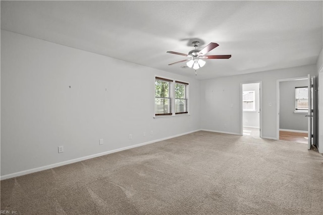 unfurnished room with baseboards, ceiling fan, and light carpet