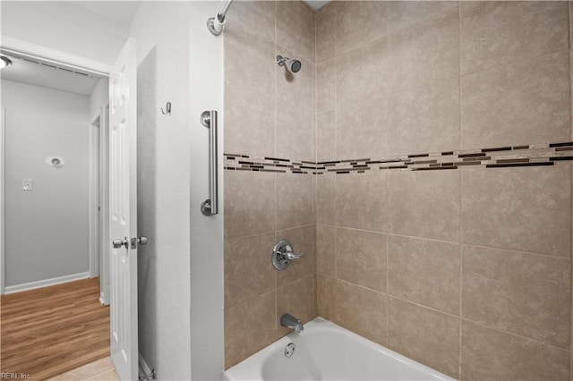 bathroom with baseboards,  shower combination, and wood finished floors