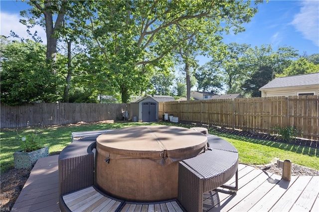 deck with a fenced backyard, a storage unit, a lawn, a hot tub, and an outbuilding
