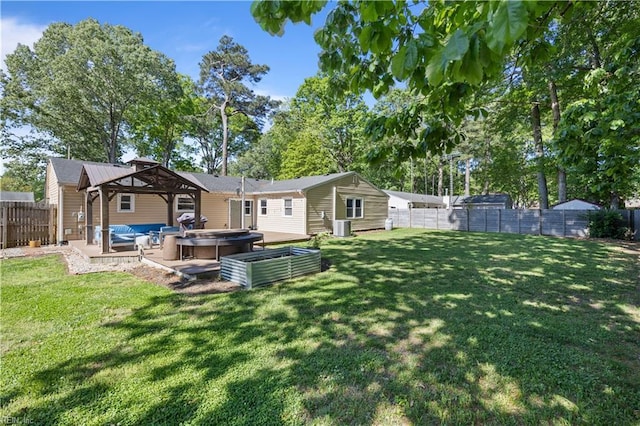 back of house featuring a hot tub, a yard, central AC unit, and a fenced backyard