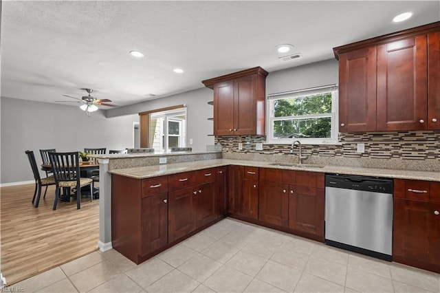 kitchen with stainless steel dishwasher, a peninsula, plenty of natural light, and a sink
