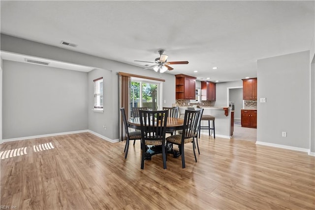 dining space with light wood-style floors, baseboards, a ceiling fan, and visible vents