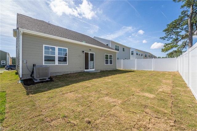 rear view of property featuring a lawn, a fenced backyard, and central AC unit