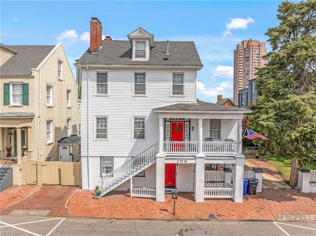 view of front of property featuring a chimney, covered porch, stairs, and a gate