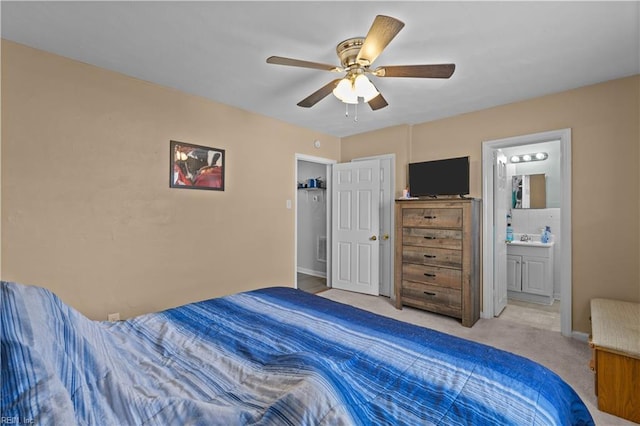 bedroom featuring ensuite bathroom, ceiling fan, light colored carpet, and a sink