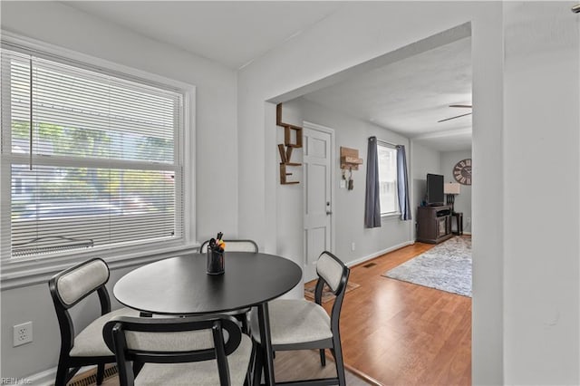 dining area with a healthy amount of sunlight, ceiling fan, light wood finished floors, and baseboards