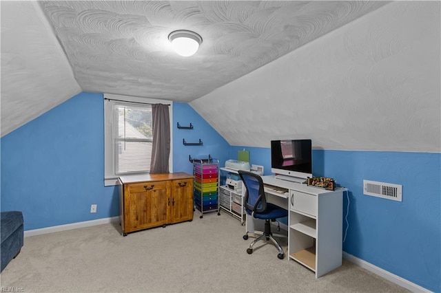 carpeted office featuring baseboards, visible vents, and vaulted ceiling
