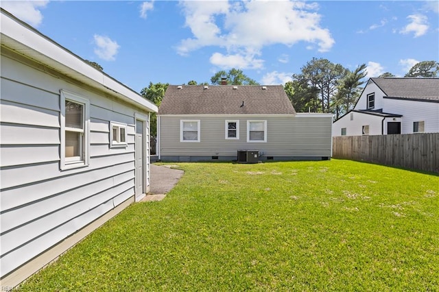 rear view of house with fence, central AC, and a yard