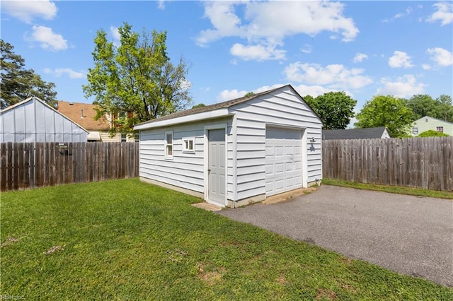 detached garage featuring fence and aphalt driveway