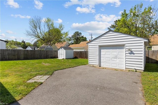 detached garage featuring fence and aphalt driveway