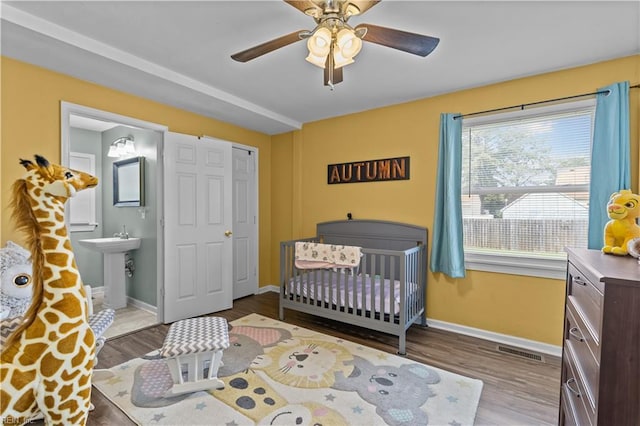 bedroom featuring baseboards, visible vents, wood finished floors, and a ceiling fan