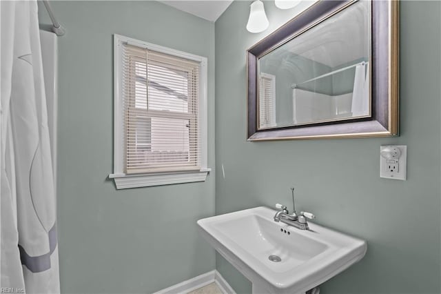bathroom with a shower with curtain, a sink, and baseboards