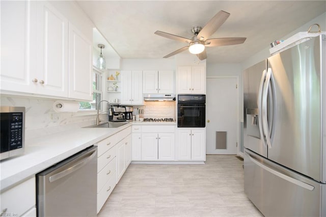 kitchen with white cabinets, stainless steel appliances, a sink, tasteful backsplash, and a ceiling fan