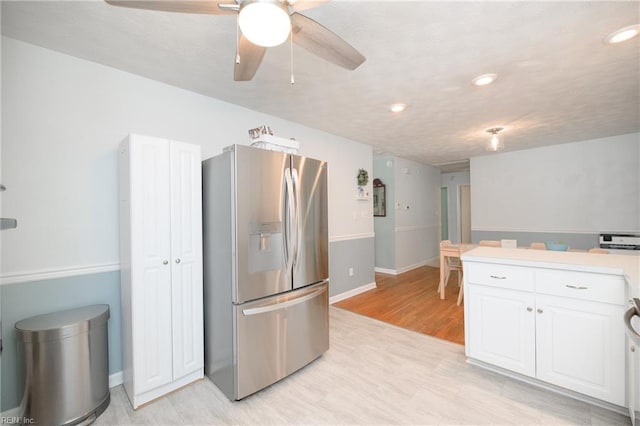 kitchen featuring white cabinets, stainless steel fridge, light wood-style floors, a ceiling fan, and light countertops