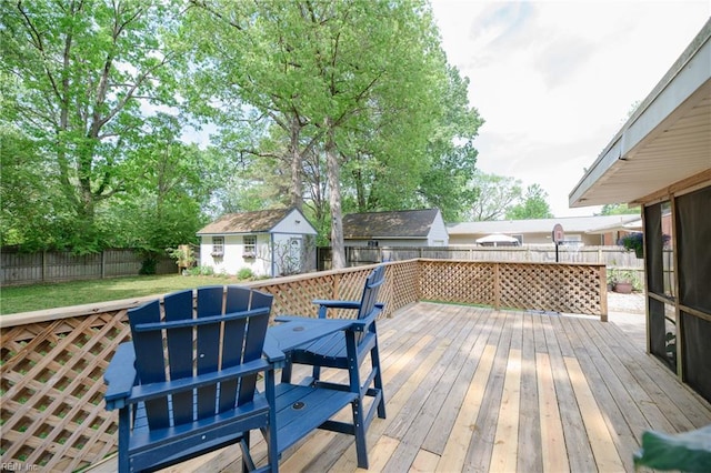 wooden terrace featuring a fenced backyard, an outdoor structure, and a shed