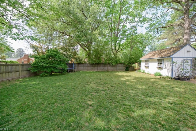 view of yard featuring an outdoor structure, a trampoline, and a fenced backyard