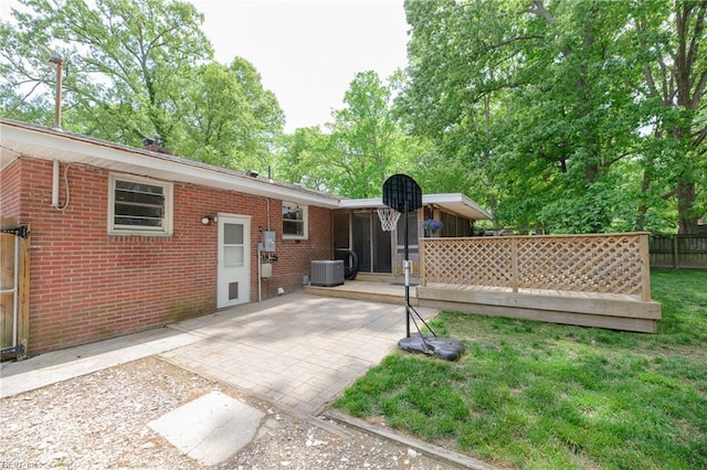 rear view of property with central AC, fence, a yard, a patio, and brick siding