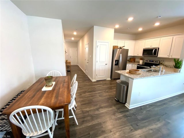1547 Stanford Ln, Newport News, VA 23608 - kitchen with appliances with stainless steel finishes, white cabinets, dark wood-style flooring, light stone countertops, and recessed lighting