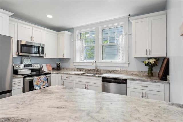 kitchen featuring light stone counters, a sink, white cabinets, appliances with stainless steel finishes, and recessed lighting