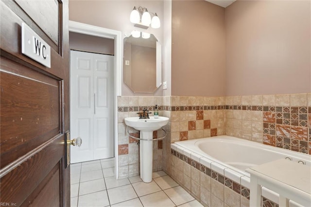 bathroom featuring a bath, tile patterned flooring, and a sink