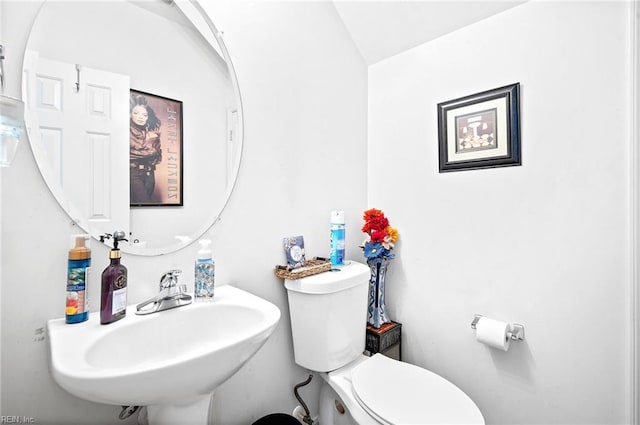 half bath with vaulted ceiling, a sink, and toilet