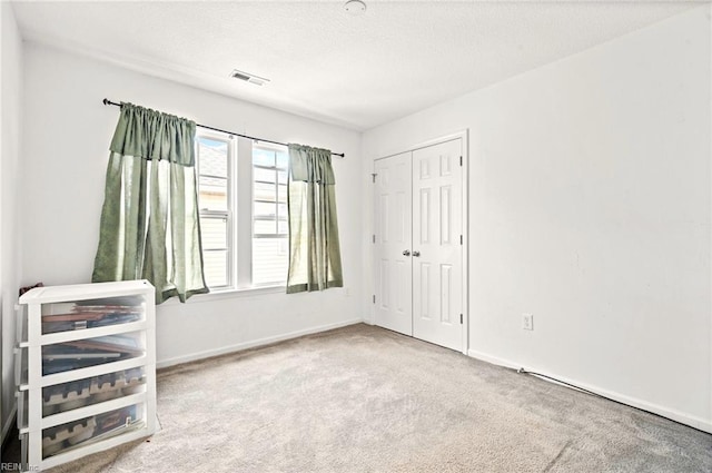 unfurnished bedroom with a closet, visible vents, carpet flooring, and baseboards