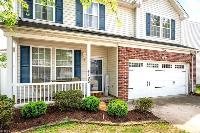 view of exterior entry featuring brick siding, a porch, driveway, and a garage