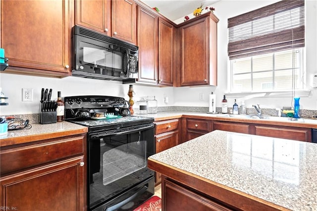 kitchen with light stone counters, a sink, and black appliances