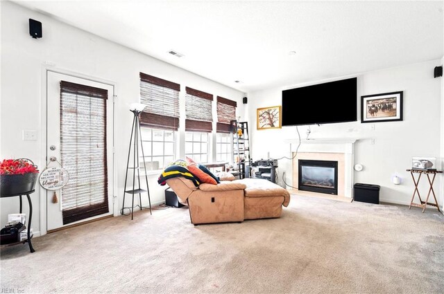 living area featuring a glass covered fireplace, baseboards, carpet flooring, and visible vents