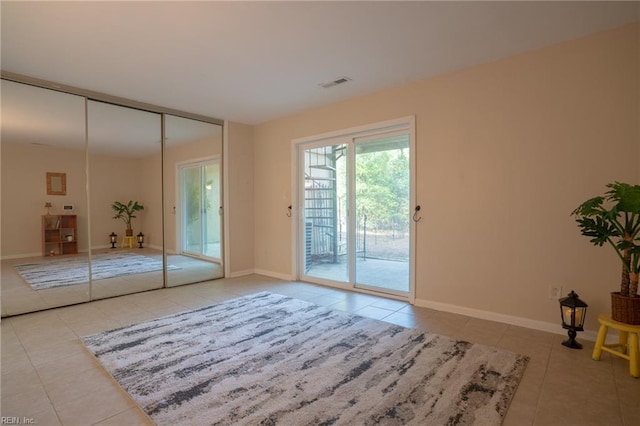 unfurnished bedroom featuring access to exterior, tile patterned floors, baseboards, and visible vents
