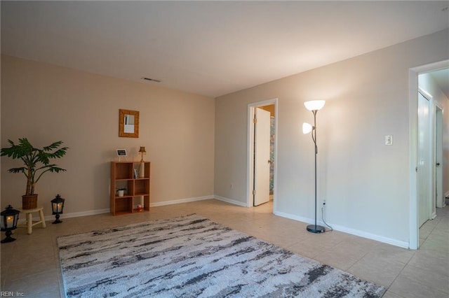 empty room with baseboards, visible vents, and light tile patterned floors