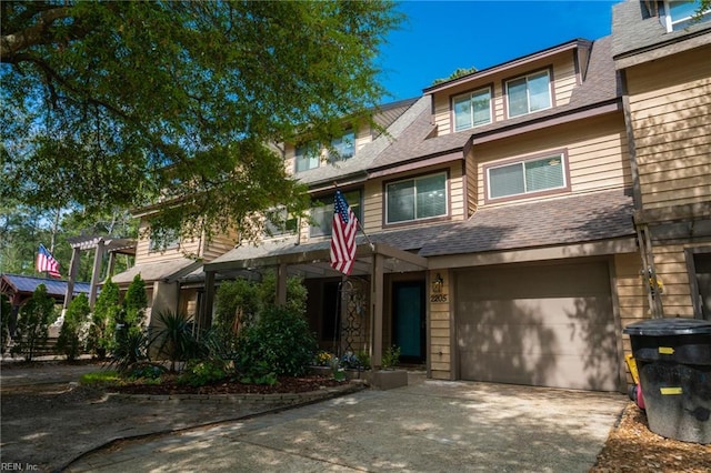 view of front of house featuring an attached garage, a shingled roof, and driveway