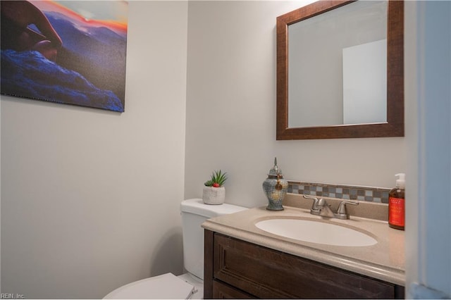 half bathroom with vanity, backsplash, and toilet