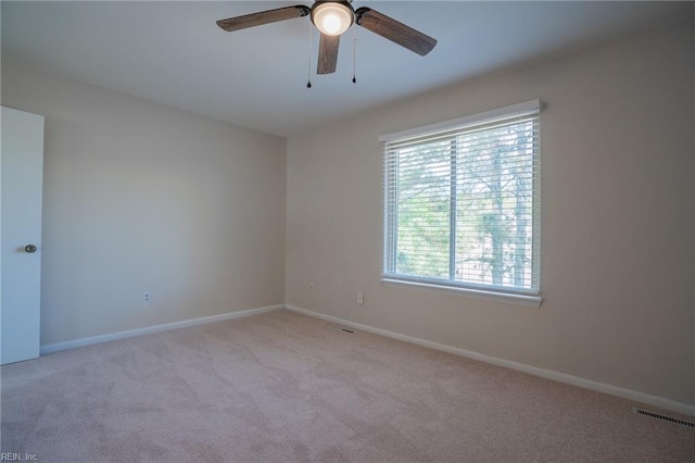 empty room featuring ceiling fan, light carpet, visible vents, and baseboards