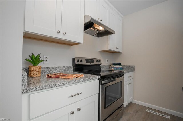 kitchen with electric range, visible vents, baseboards, wood finished floors, and under cabinet range hood