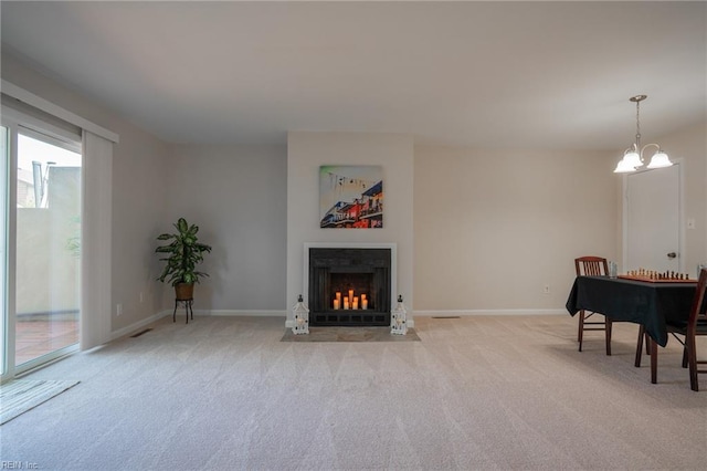 living area featuring a fireplace with flush hearth, baseboards, visible vents, a notable chandelier, and light colored carpet