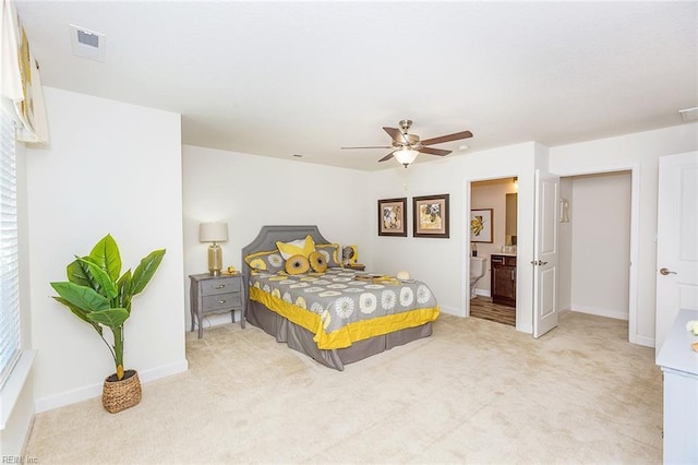 carpeted bedroom featuring baseboards, a ceiling fan, ensuite bath, and visible vents