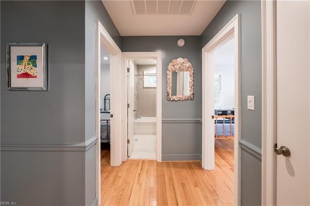 hallway featuring visible vents, baseboards, and light wood-style floors