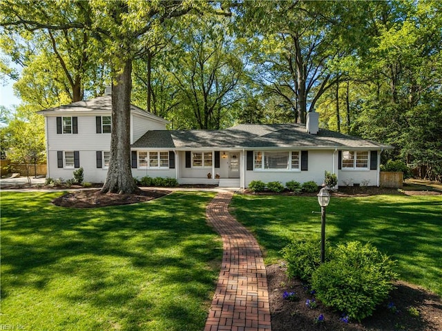 view of front of home featuring fence, a chimney, and a front lawn