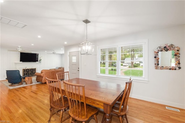 dining room with baseboards, visible vents, light wood-type flooring, and a fireplace