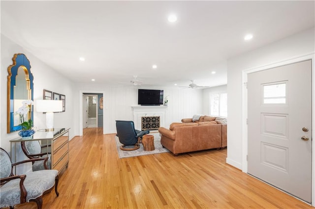 living room with recessed lighting, a fireplace, light wood finished floors, baseboards, and a ceiling fan
