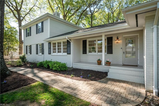 view of exterior entry featuring covered porch and brick siding