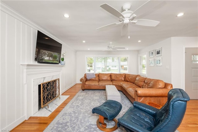 living area featuring a high end fireplace, recessed lighting, ceiling fan, and light wood-type flooring