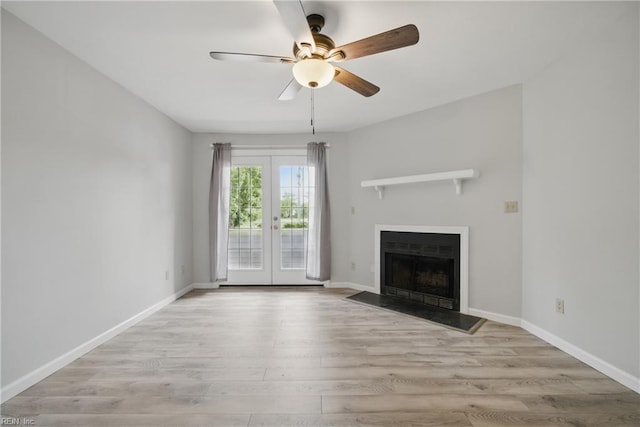 unfurnished living room with ceiling fan, french doors, baseboards, a fireplace, and wood finished floors