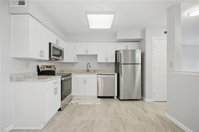 kitchen with white cabinets, a sink, visible vents, stainless steel appliances, and baseboards
