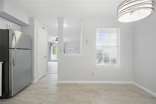 unfurnished dining area with ceiling fan, visible vents, and baseboards