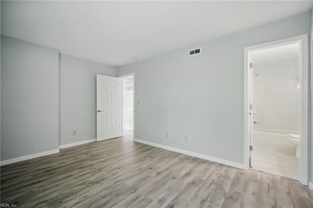 spare room with baseboards, visible vents, and wood finished floors
