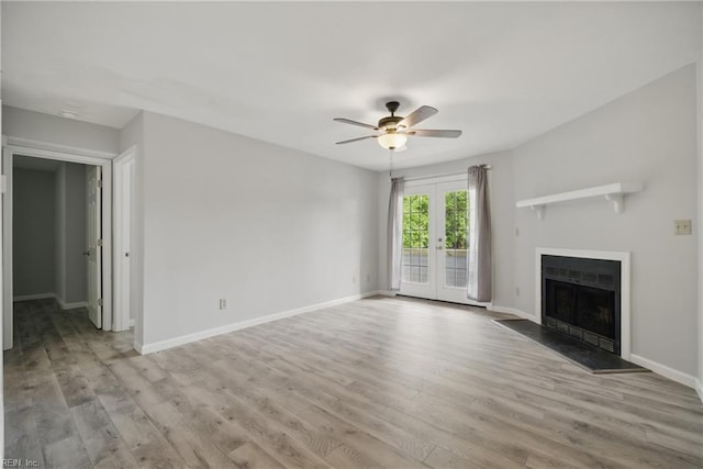 unfurnished living room with a ceiling fan, light wood-style flooring, french doors, and a fireplace