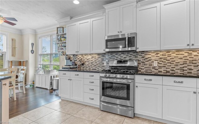 kitchen featuring dark countertops, a ceiling fan, stainless steel appliances, and light tile patterned floors