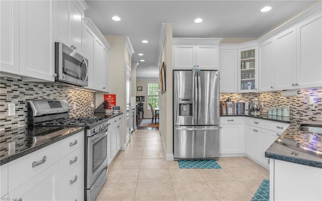 kitchen with appliances with stainless steel finishes, tasteful backsplash, white cabinetry, and light tile patterned floors